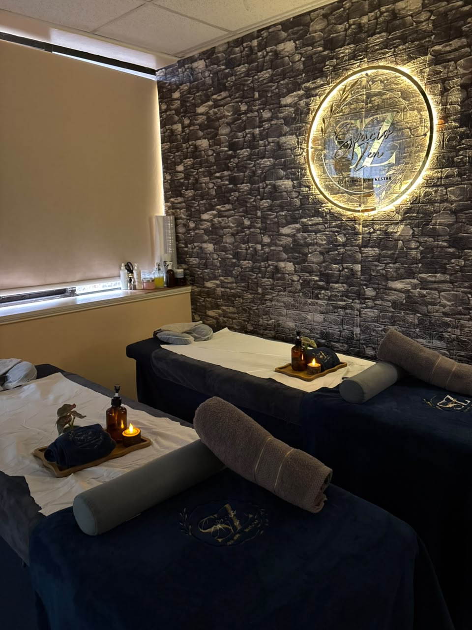 Sala de masajes doble con velas y logo Spacio Zen