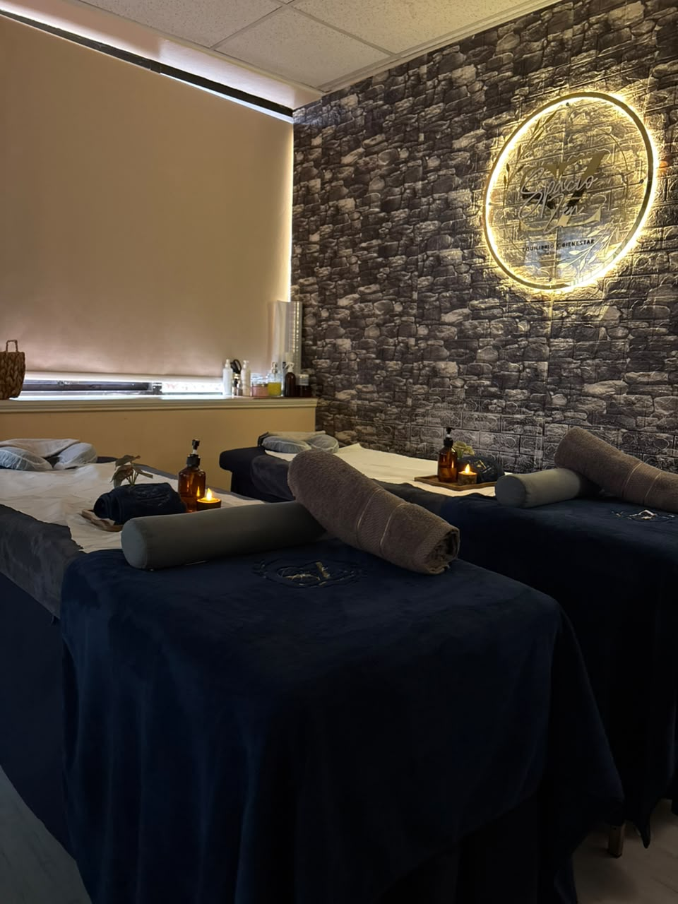 Sala doble con pared de piedra y logo iluminado Spacio Zen